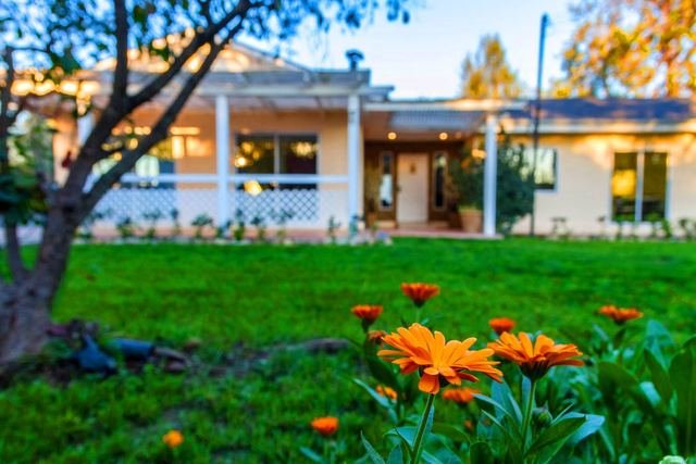 Flores naranjas en primer plano y la casa iluminada al atardecer detrás
